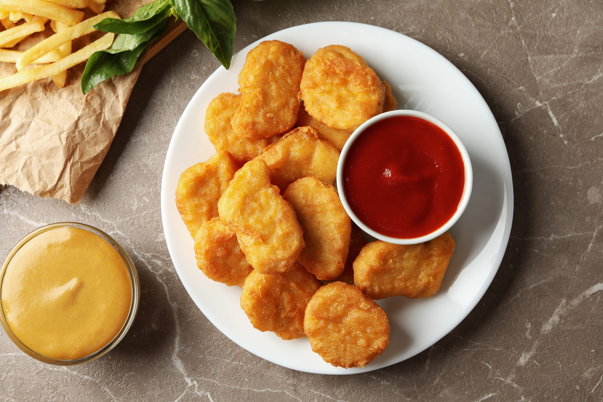 Composition with Chicken Nuggets, Potato and Sauces on Gray Tabl